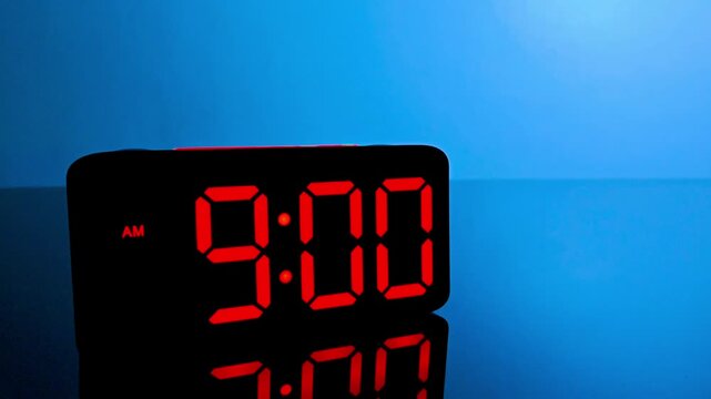 Digital alarm clock changing from 8:59 am to 9:00 am with red led display
