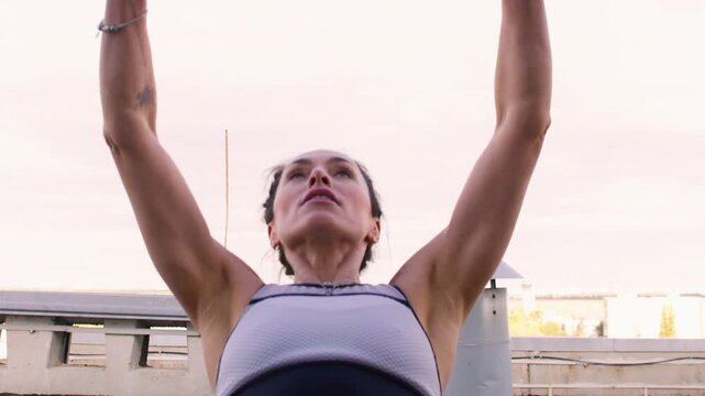 Bodybuilding training. Urban fitness. Athlete female on rooftop performing physical exercise using suspension straps strengthening back biceps.