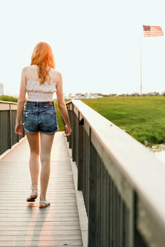 young woman walking down a bridge towards American Flag
