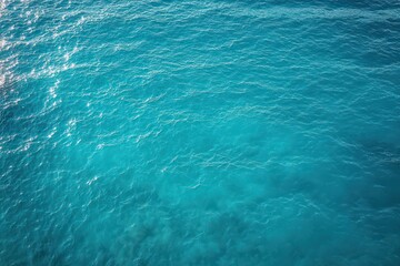 Fototapeta premium Aerial view of turquoise ocean water with gentle ripples and shimmering sunlight evoking calm serenity