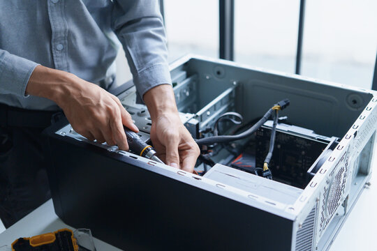 Asian IT support engineer using screwdriver fixing broken part in pc