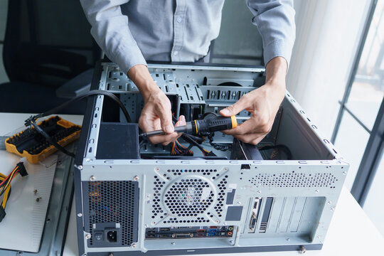 Asian IT support engineer using screwdriver fixing broken part in pc