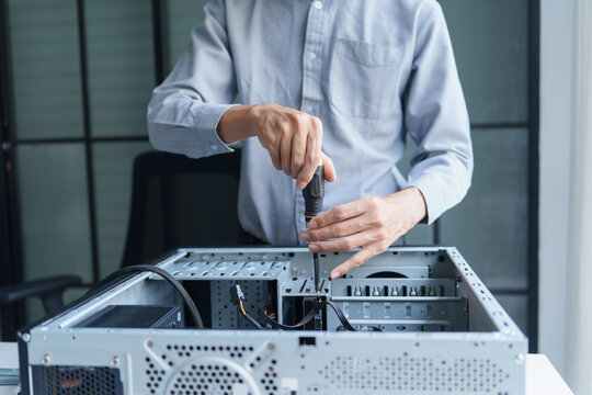 Asian IT support engineer using screwdriver fixing broken part in pc