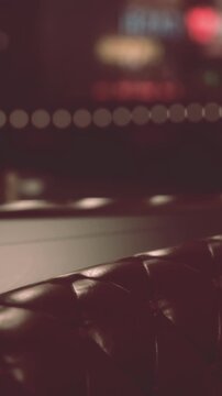 The scene shows a close view of a chair in a bar. In the background, colorful lights create a lively atmosphere. The setting appears to be night, making the lights stand out.