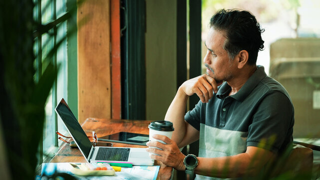 Senior Entrepreneur Reviewing Business Reports While Working in Coffee Shop