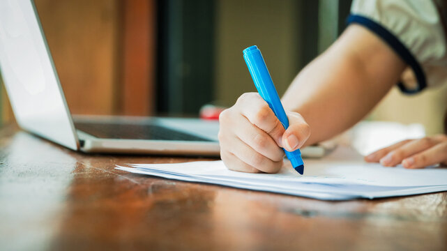 Close Up of Hand Writing Notes During Business Meeting with Laptop on Desk