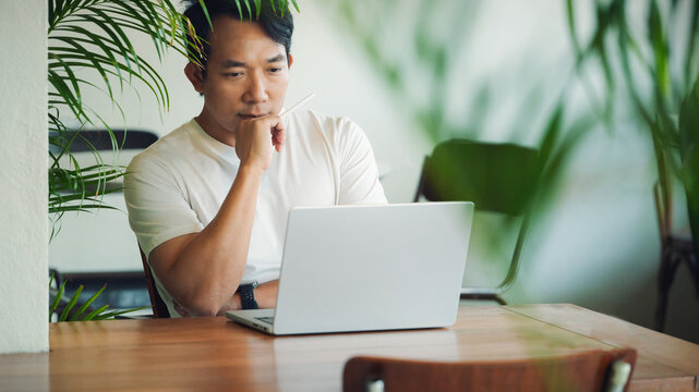 Focused Business Professional Thinking While Working on Laptop in Modern Office