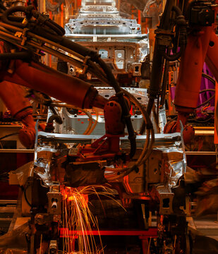 Robotic arms are welding points on the car body on an automated production line.