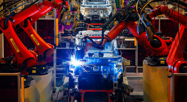 Robotic arms are welding points on the car body on an automated production line.
