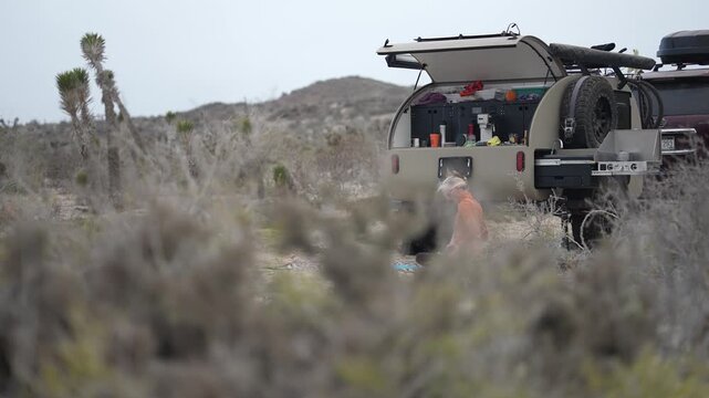 Happy woman practices yoga in desert of Baja California by her teardrop camper trailer while enjoying the outdoor setting