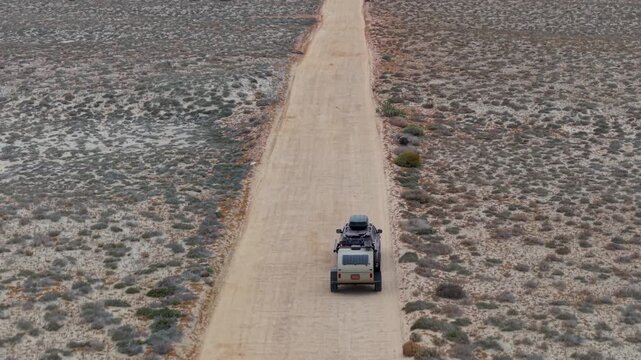 An suv pulls a teardrop camper trailer overland through the Baja California Mexico desert while exploring sandy roads and rocky terrain