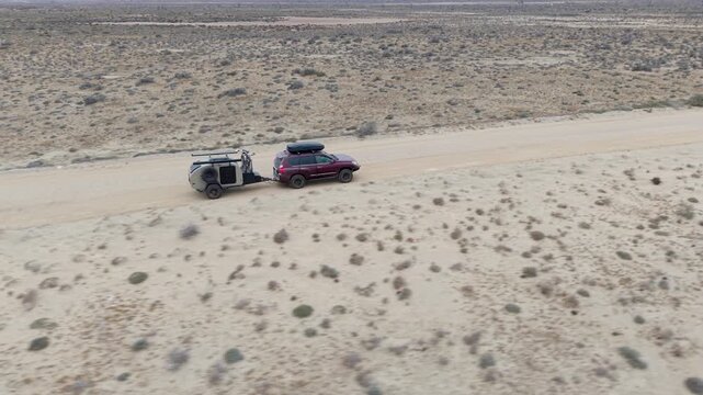 A suv pulls a teardrop camper trailer overland through the desert landscape of Baja California Mexico, highlighting the adventure of camping.