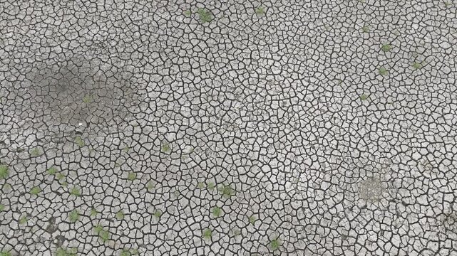 Aerial view of a dry pond featuring natural cracked soil formations and barren terrain in rural Bangladesh. Ideal stock footage for themes including drought and global warming.