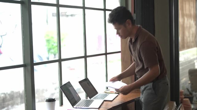 Young Man Working on Laptop Computer at Desk in Modern Office or Home Workspace, Using Technology for Online Business, Internet Research, and Digital Lifestyle Activities