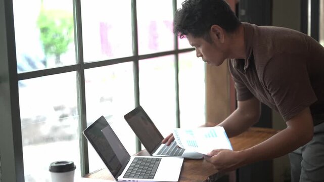 Young Man Working on Laptop Computer at Desk in Modern Office or Home Workspace, Using Technology for Online Business, Internet Research, and Digital Lifestyle Activities