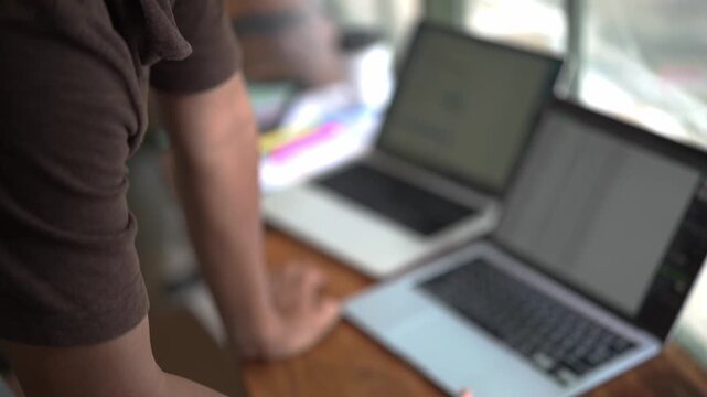 Young Man Working on Laptop Computer at Desk in Modern Office or Home Workspace, Using Technology for Online Business, Internet Research, and Digital Lifestyle Activities