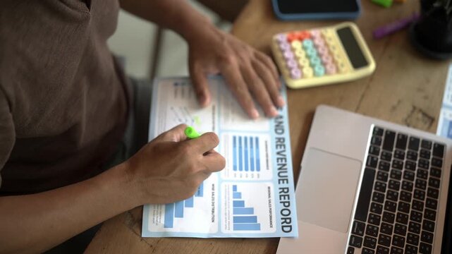 Hand Holding Pen Marker with Financial Graphs for Business Data Analysis, Technology, Research and Office Work Concept