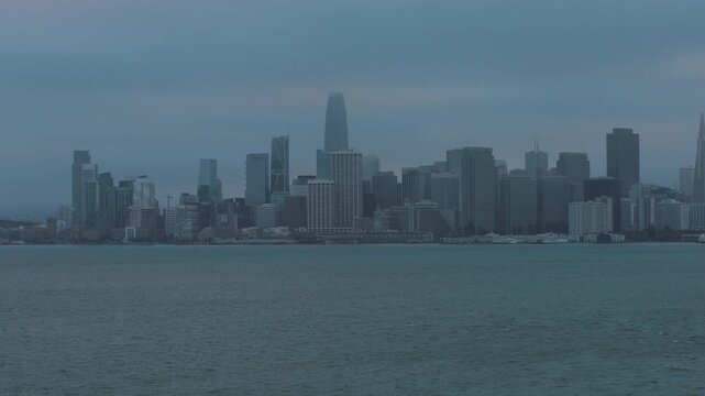 Rain storm over view of silhouetted San Francisco skyscrapers and bay - Drone backwards shot