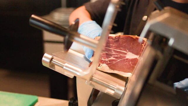 Professional Chef Slicing Cured Meat with Electric Deli Slicer