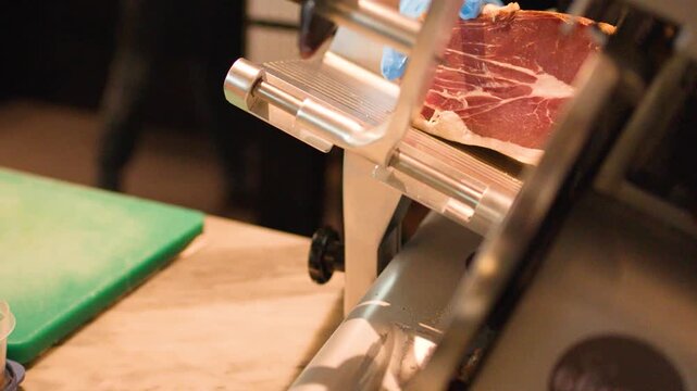 Professional Chef Slicing Cured Ham with Electric Meat Slicer