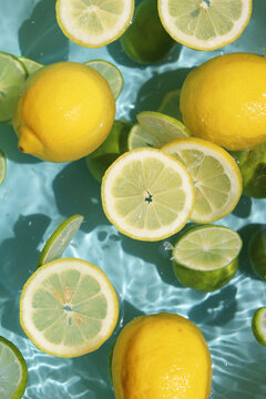 Lemons and limes floating in blue water