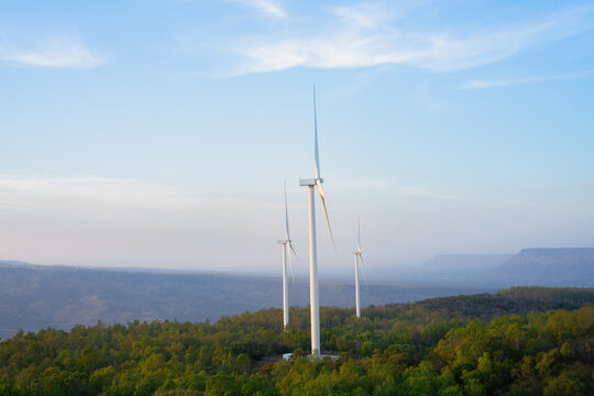 Wind turbines generating renewable energy on forest landscape, clean electricity and sustainable power concept.