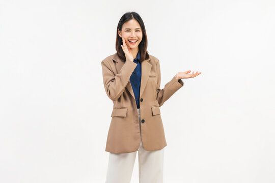 Smiling young Asian businesswoman presenting empty space with open palm and cheerful expression isolated on white background.