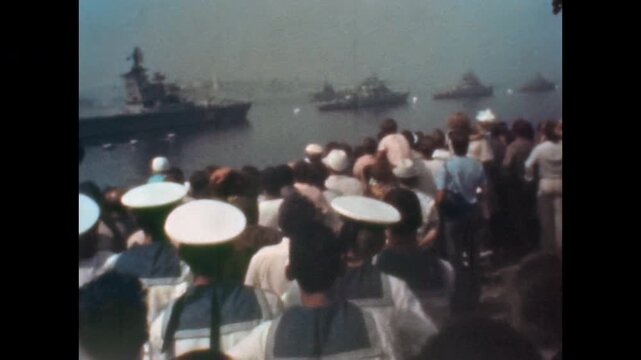 Soviet union military navy parade in Ukraine Odessa in 1960s. Sailors, civilians crowd on coast watching aircraft carrier, warships at naval event parade. Old film. Archival retro. Vintage archive