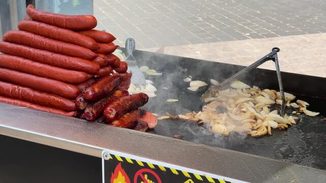 Sausages and Onions Grilling on a Flat Top Outdoor Griddle