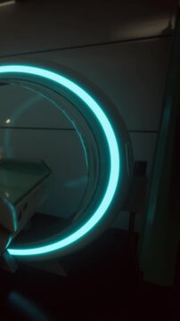 A round device with bright light is seen in a clinical room. The device appears to be positioned next to a bed and may be used for medical scans or treatment.