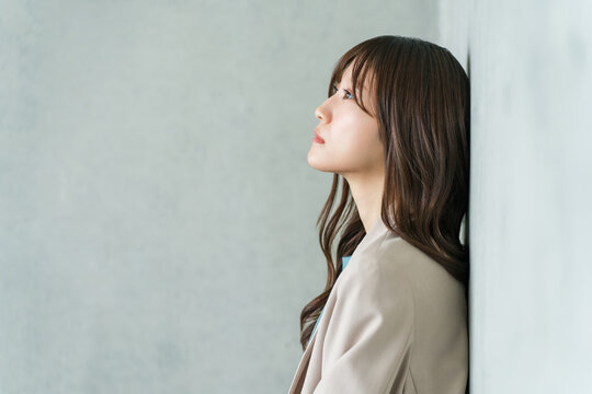 A young Asian businesswoman looks up, deep in thought.