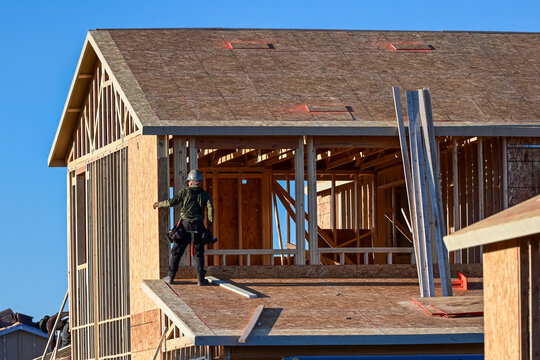 Construction worker on the second floor of a two story single-family home under construction in a new residential subdivision, representing residential framing, elevated work, and housing development