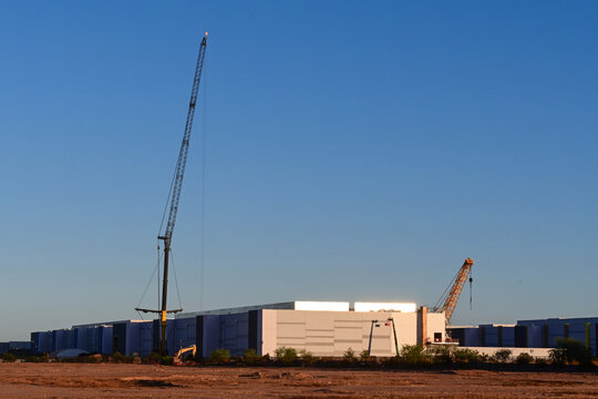 Large data center campus under construction with mobile cranes, prefabricated equipment modules, and utility infrastructure, representing digital infrastructure expansion and cloud computing developme