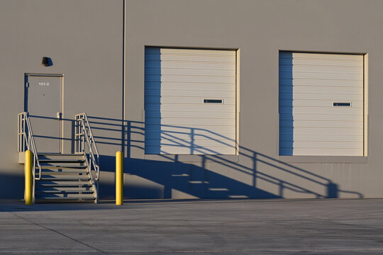 Loading dock doors with an accessible ramp and stairway at a commercial warehouse, representing industrial logistics, freight distribution, and warehouse infrastructure