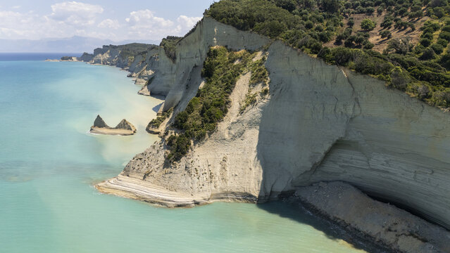 Aerial view of the dramatic limestone cliffs and turquoise waters of Loggas beach in Corfu, Greece.