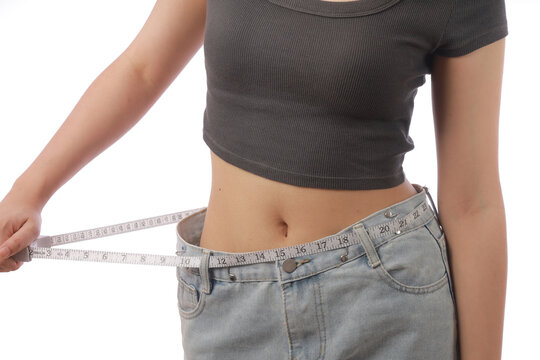 Weight loss clinic concept with woman measuring waist using tape showing loose jeans and slim body healthy lifestyle