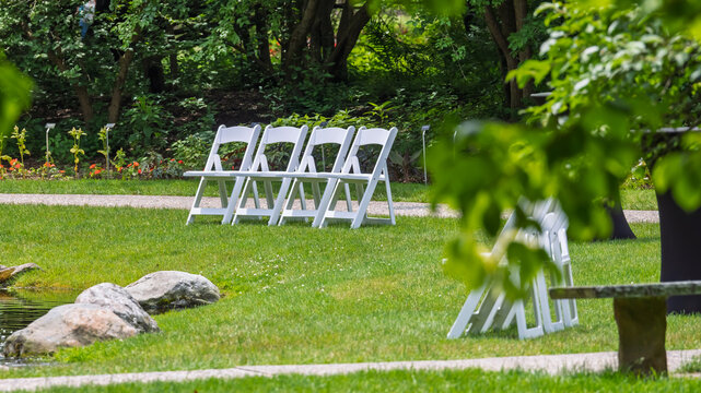 White folding chairs arranged for an outdoor garden event