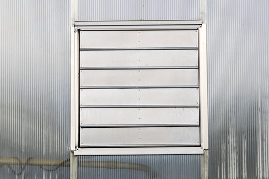 Industrial exhaust vent metal louver on greenhouse wall
