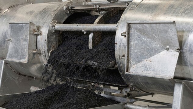 Closeup medium shot of a drum dryer cooling black pellets with open access panels revealing internal mechanics and pellet flow