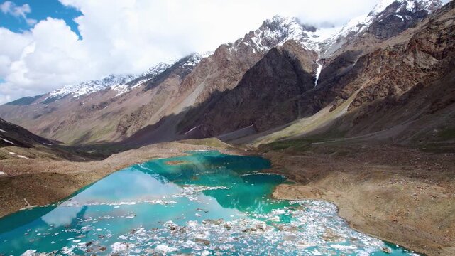 4K aerial landscape of turquoise blue Ghepan lake with small icebergs floating on its surface. Snow-capped peaks and High altitude glacial lake at Lahaul, Himachal Pradesh, India. Travel India concept