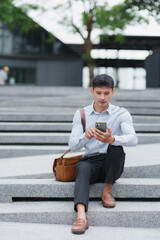 Obraz premium Young man sitting on stairs using smartphone device