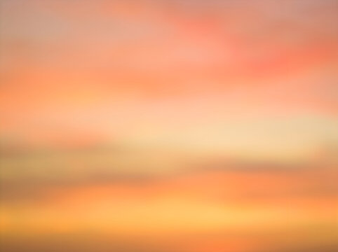 Sunset sky with warm orange and pink clouds over calm ocean horizon