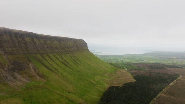 Cinematic drone shot of Ben Bulben table mountain in Sligo, Ireland. Famous flat-topped landmark with green countryside and majestic rock cliffs.