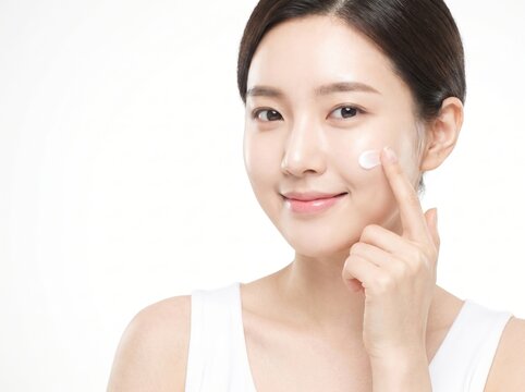 Beautiful Young Asian Woman Applying Face Cream Cream on Cheek for Skincare Routine