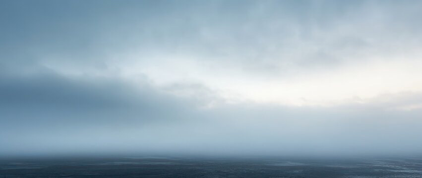 foggy seascape with calm dark ocean, low horizon and brooding overcast sky conveying solitude and melancholy