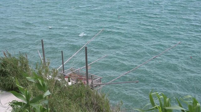 Traditional trabucco fishing machine on the coast of Vieste. Aerial view of a historic trabucco, a fishing machine on the Gargano coast, over a choppy sea