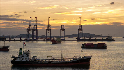 Fototapeta premium massive fleet heavy oil tankers and LNG vessels anchored at a strategic maritime chokepoint during a golden sunset, emphasizing global energy crises and petroleum supply chain infrastructure.