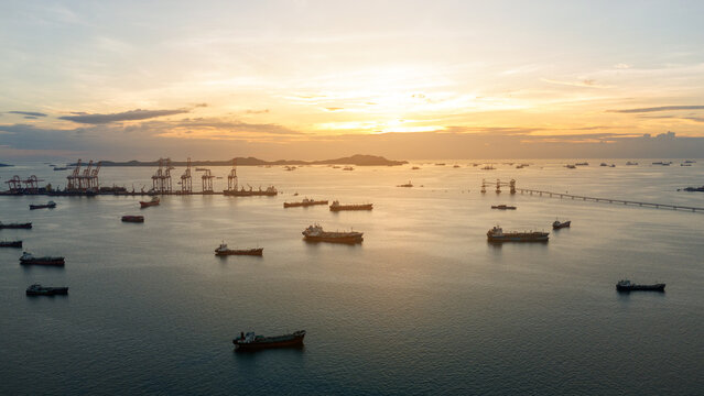 massive fleet heavy oil tankers and LNG vessels anchored at a strategic maritime chokepoint during a golden sunset, emphasizing global energy crises and petroleum supply chain infrastructure.