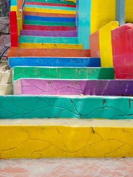 Brightly painted staircase with vivid rainbow colors, textured surface and artistic design creating cheerful visual impact. Background or backdrop texture. Copy space for text 