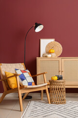 Interior of living room with wooden commode, armchair and pumpkins